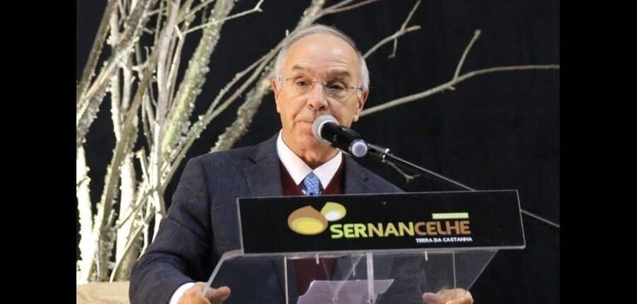 Homem a falar num evento, com um painel a dizer 'Sernancelhe' ao fundo.