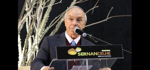 Homem a falar num evento, com um painel a dizer 'Sernancelhe' ao fundo.